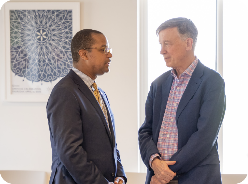 Two older men in suits talking to each other.